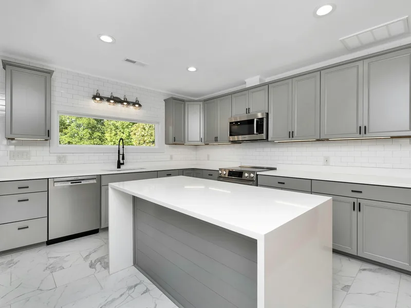 A finished kitchen with grey cabinets, white counters and a large island