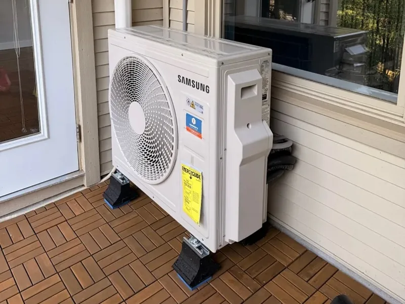 An outdoor air conditioning unit installed on rubber mounts on a balcony